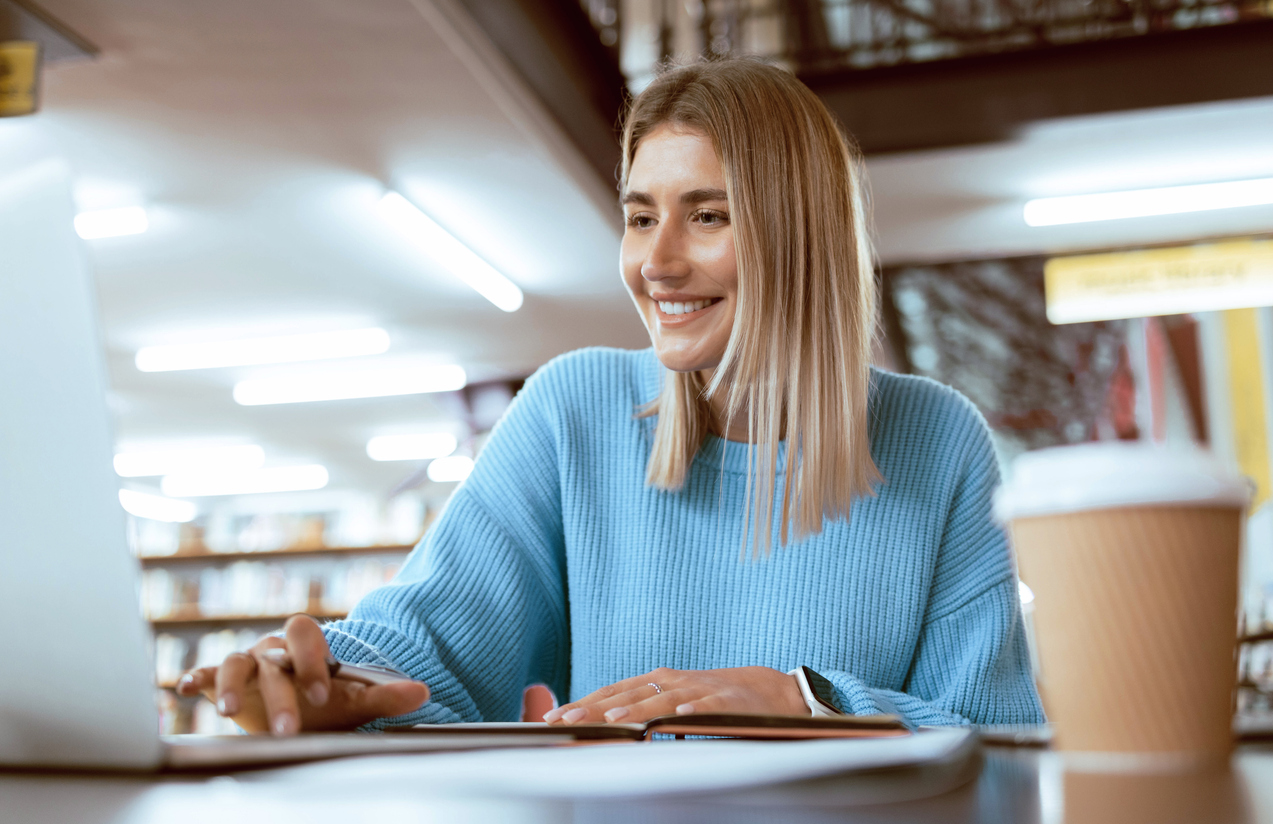 A Nursing Student Smiling and Working on a Laptop.