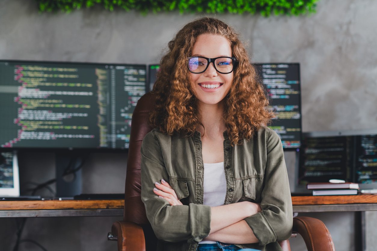 A Smiling Cybersecurity Professional in Front of Monitors Displaying Code.