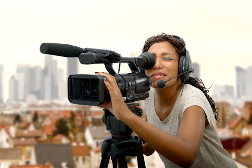 A multimedia journalist looks through a video camera.