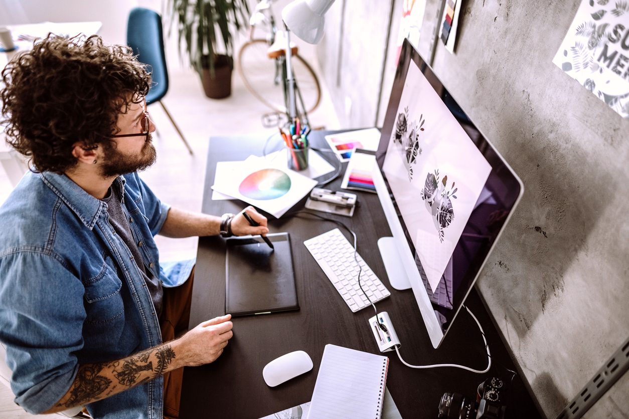 A graphic designer creates a logo using a drawing tablet and a PC.