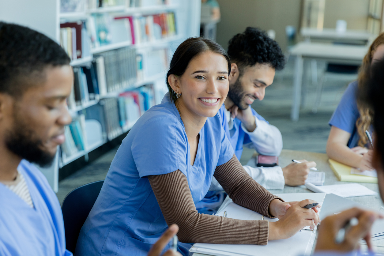 Smiling Nursing Students Study at a Table.