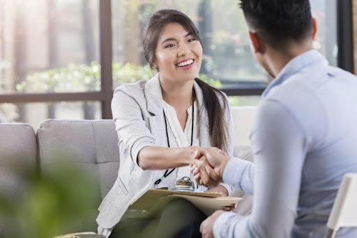 During an introduction before a counseling meeting, a psychologist shakes hands with a patient.