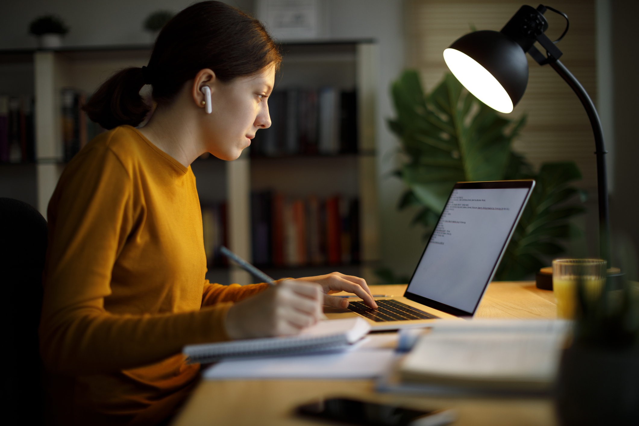 Cybersecurity student working at home on a laptop.