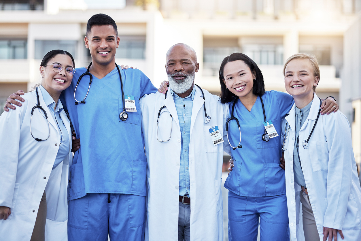 A diverse team of nurses and doctors standing outside a medical facility. 
