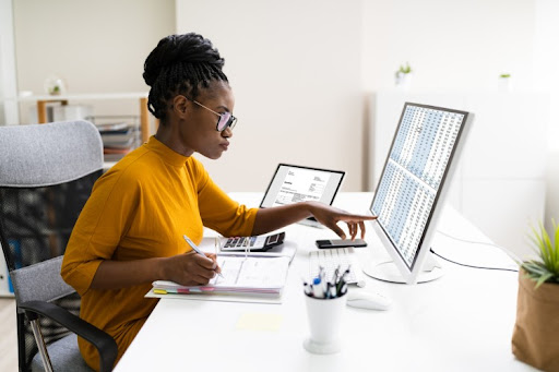 A finance degree holder analyzes rows of numbers on a computer screen.