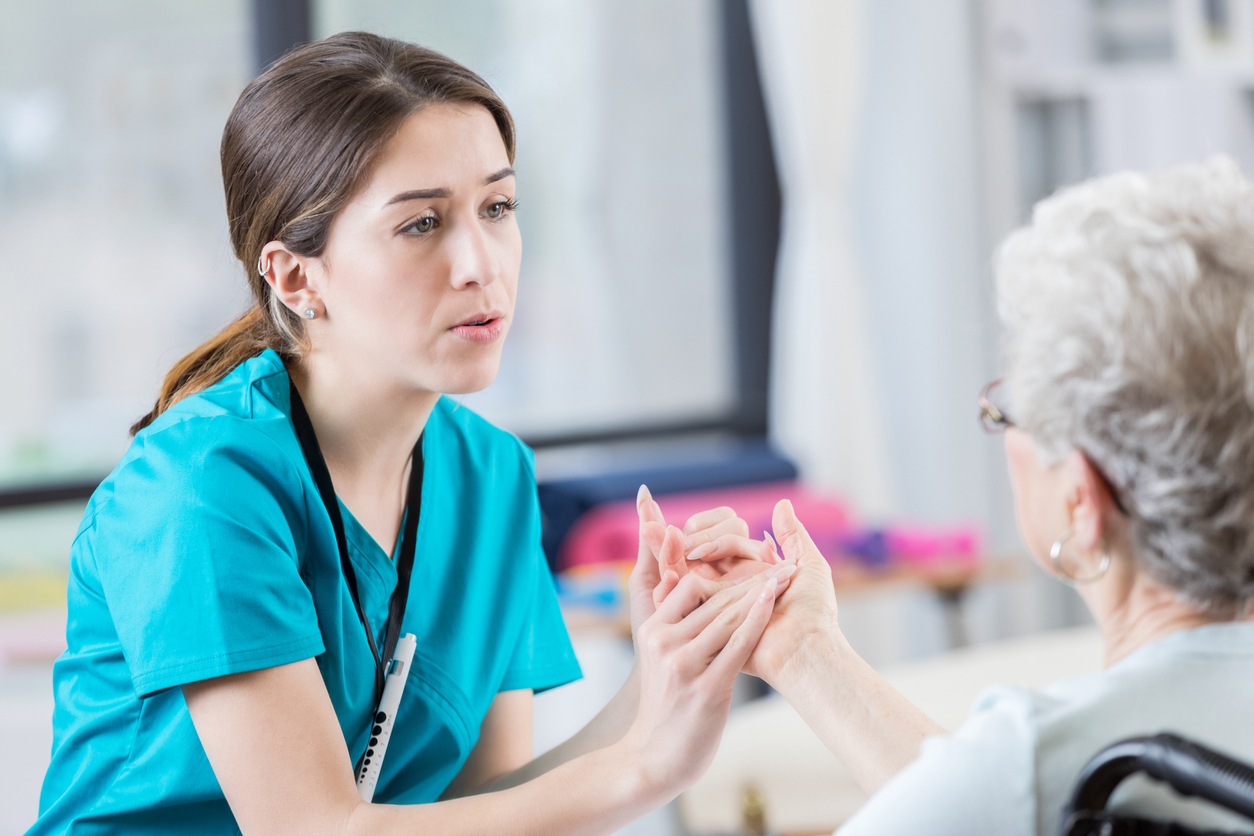 A Nurse in Blue Scrubs Gives a Hand Massage to an Older Patient.