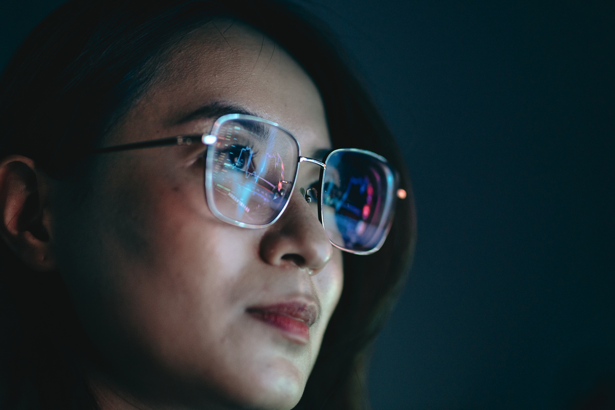 A Close up of a Cybersecurity Professional With the Reflection of a Computer Screen on the Lenses of Their Glasses.
