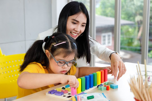 A special education teacher interacts with a student playing with blocks.