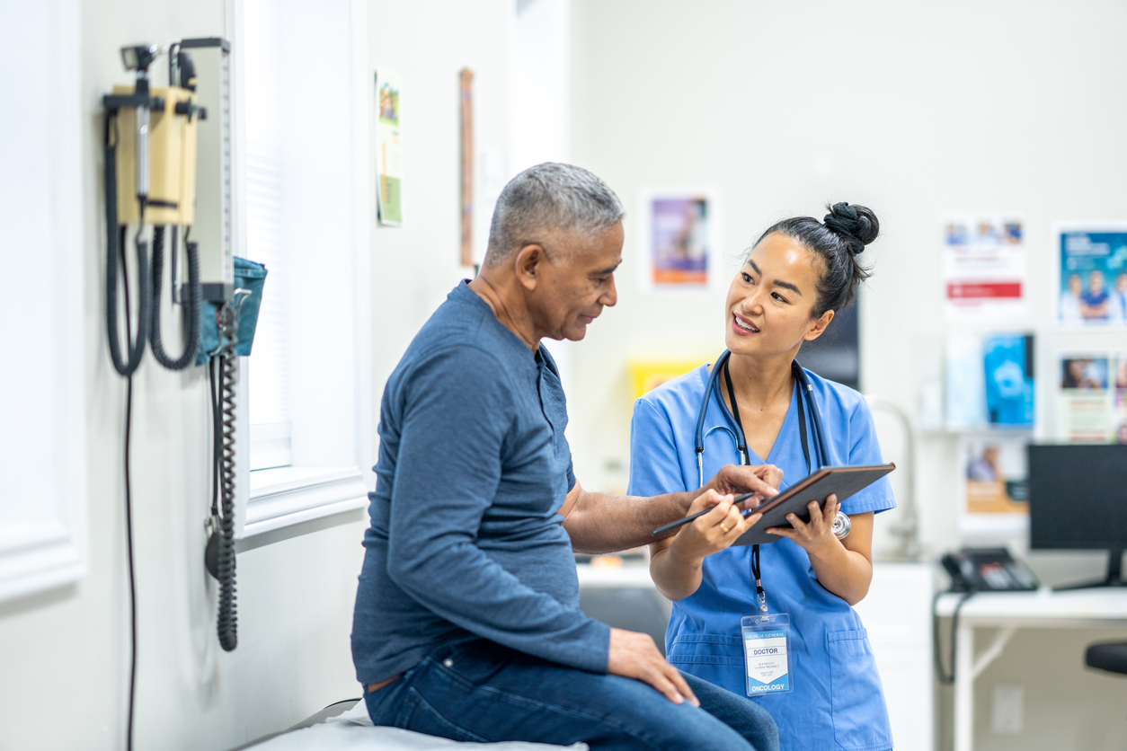 A nurse advocate uses a tablet to explain a diagnosis to a patient.