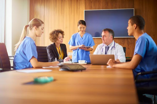 A team of nurses sitting with a doctor and a lawyer in a conference room.