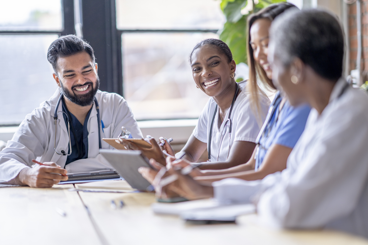 Health care professionals smiling and collaborating at a table. 