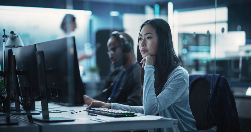 A cybersecurity professional reviews code on a monitor.