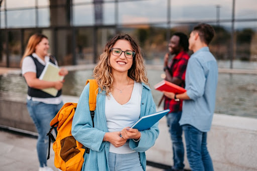 A smiling college student holding a notebook.