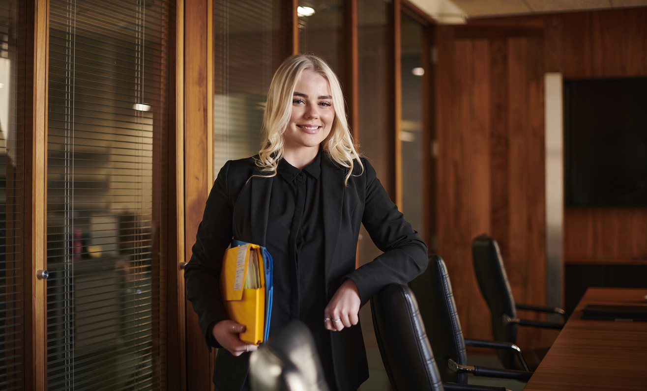 A paralegal holding folders in a conference room.