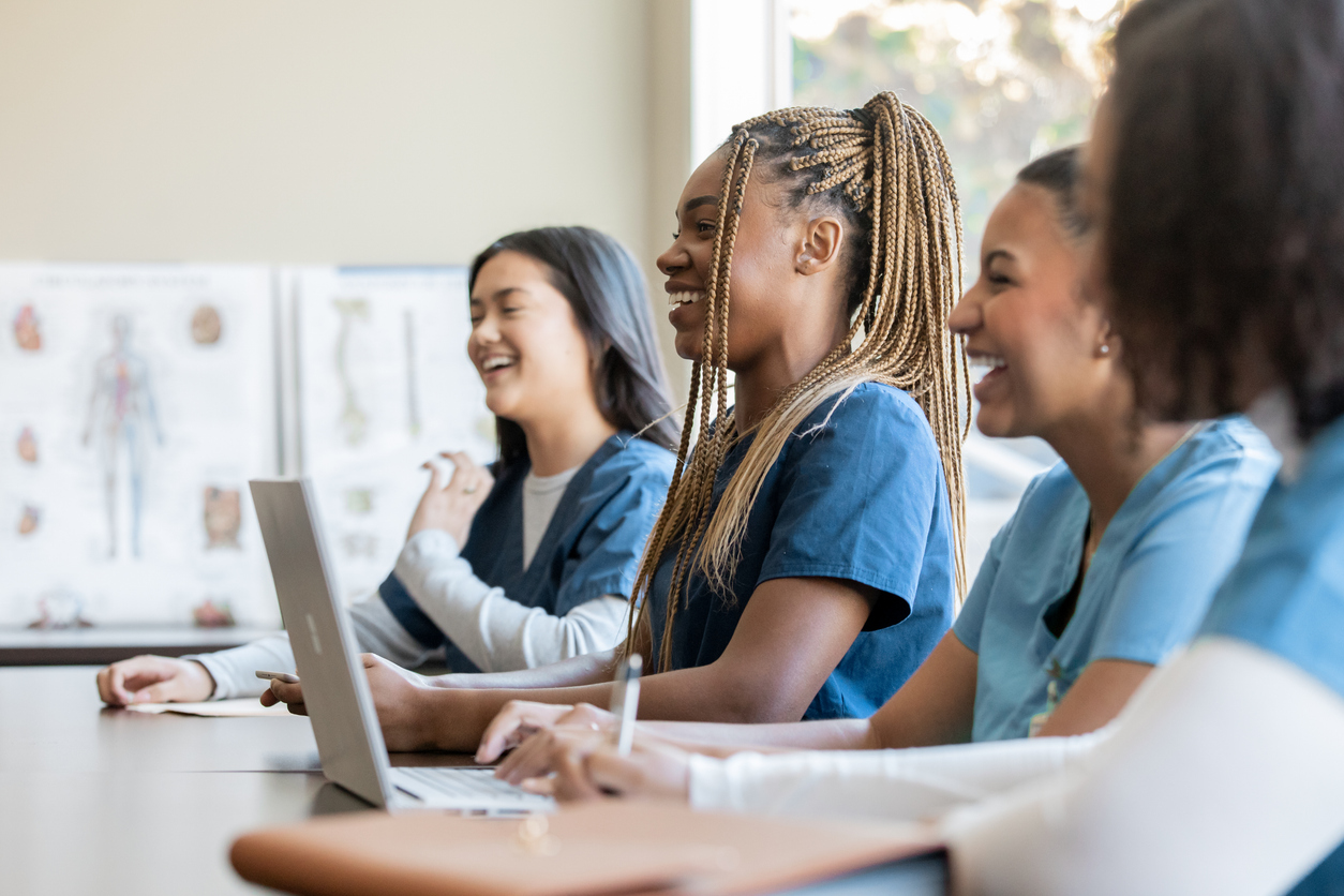 Smiling nurses taking notes in a classroom.