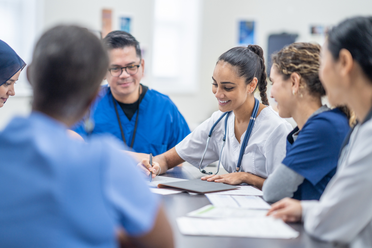 Nursing Students Share Notes While Gathered Around a Table at the Hospital.